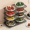 Suporte multifuncional de vários níveis para preparação e armazenamento de utensílios de cozinha, incluindo tigelas, pratos, panelas quentes, travessas e legumes.