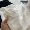 Camiseta Floral Vazada Estilo Coreano Nova Verão 2026, Respirável e Levemente Transparente, Manga Curta Versátil, Top Branco para Atacado