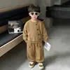Conjunto casual simple estilo coreano para primavera y otoño para niños, que consta de una camisa de manga larga de color liso con botones y pantalones tipo jogger holgados.