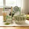 Tazón de té de cerámica texturizado de col blanca tridimensional con pico, emparejado con un soporte para batidor de té del mismo color, múltiples accesorios para la preparación de matcha