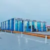 En invierno, se utiliza el dispositivo de limpieza de neumáticos de salida de agua a alta presión para vehículos modernos en la puerta del parque logístico.