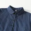 Foto real del nuevo vestido casual de otoño 2026 estilo japonés de longitud media con cuello de solapa, cintura de corbata, mangas largas y tela de algodón y lino a rayas
