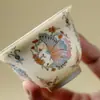 En las montañas, pinos y mariposas danzan entre las flores.; un cuenco de té de cerámica pintado de rosa, hecho a mano con un cuerpo delgado que no quema la mano, es parte del juego de té Kung Fu