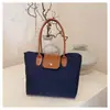 Bolsa de mano de nailon de color contrastante estilo coreano, cuerpo de bolsa de nailon con detalles de cuero marrón y un dije de cachorro de peluche, bolso de hombro para estudiante