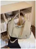 Bolsa tote versátil, minimalista e espaçosa com bolsos, perfeita para um look de verão moderno e casual.
