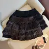Foto real de la nueva colección otoño/invierno 2026: una falda corta de mujer acampanada con un diseño de patchwork de terciopelo y encaje, con cintura elástica