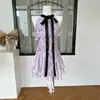 Top sin mangas y falda de color contrastante violeta satinado brillante uva con volantes y lazo