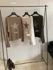 Dela, uma coleção de outono doce apresentando um suéter de malha feminino estilo retro americano com padrões de estrelas, enfeites de rebites e um design de ombro assimétrico, mangas compridas e um preço de 67000