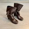 Nova coleção 2026: Botas femininas de cano médio com tiras e saltos grossos, perfeitas para outono e inverno, apresentando um design emagrecedor com detalhes plissados e um visual de salto alto estilo equestre.