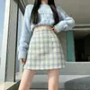 Foto real de saia curta xadrez estilo francês levemente maduro para outono de 2026, para mulheres baixinhas, saia bodycon evasê emagrecedora estilo Chanel