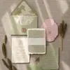 Convite de casamento em papel de algodão feito à mão com bordas irregulares, color-blocking nas cores verde e rosa Morandi, com forro do envelope em relevo e ilustração