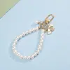 Chaveiro de pulseira de pérola estilo Chanel para meninas com laço em formato de coração, flor e pingente de metal acessório de bolsa