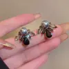 Brincos únicos e estilosos em formato de pétala preta com detalhes em diamante e pérola, um design de alta qualidade e uma nova tendência de 2026