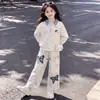 Conjunto elegante de dos piezas: top estilo universitario, oversized, de manga larga, con un diseño moderno, combinado con pantalones casuales de estampado retro de mariposas.