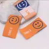 Rosto sorridente colorido marca tecida etiqueta de tecido etiqueta traseira corda de cabelo diy elástico etiqueta grampo de cabelo material de decoração para adorno de cabeça acessórios