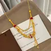 Colar banhado a ouro com detalhes em ouro areia e rubi, projetado para durar sem desbotar, apresentando uma corrente delicada e luxuosa para a clavícula com um pingente de trevo de quatro folhas