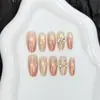 Nova arte de unha estilo gatinho com bolinhas de pêssego, formatos oval curtos, médios e longos, com design de laço, em cores nude, criando um visual estiloso e atmosférico