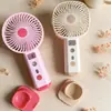 Ventilador de mano nuevo, simple y elegante, con rociador hidratante y tres velocidades de viento, que cuenta con una base de carga directa para teléfono, perfecto como ventilador de escritorio y como regalo