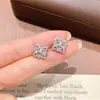 Pendientes de botón de trébol de cuatro hojas huecos con baño de oro champán de venta caliente en Xiaohongshu, adornos para la oreja simples para el día a día con circonita incrustada