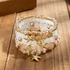Pulseras multicapa al por mayor, juego de cuatro piezas de joyería con cuentas de artesanía en vidrio, juego de pulseras elásticas, accesorio de mano con soporte de flor de hierro