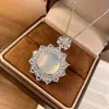Colgante de calcedonia tipo hielo totalmente incrustado con diamantes para mujer, con una vibrante gema pequeña de ojo de gato verde y blanca, un delicado collar y una cadena para la clavícula, ofreciendo un toque de lujo discreto.