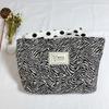 Versión coreana de bolsa de maquillaje de vaca en blanco y negro, bolso de mano jacquard, tendencia de alto valor, bolsa de almacenamiento portátil con acabado para viajes, venta al por mayor