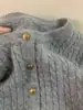 Suéter de punto de cable gris de alta gama con textura afelpada, perfecto como capa interior o exterior para mujeres en otoño e invierno, con un estilo relajado y pequeños botones dorados