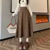 Foto real de falda de gamuza de estilo coreano para otoño/invierno 2026, de cintura alta, que cubre la cadera, adelgazante, hasta la rodilla, de longitud media, con un dobladillo grande