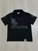 Camiseta de Verano de Manga Corta Estilo Ins Transfronterizo con Calavera de Pedrería Oscura, Diseño de Hebilla Metálica Lateral y Cuello Solapa, Top de Corte Holgado