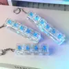 Llavero creativo de alta transparencia con cuatro botones y probador de interruptor iluminado, gadget para aliviar el estrés, juguete colgante transparente iluminado, regalo
