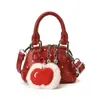 Bolsos de concha estilo coreano para niños y niñas con elegantes lunares y pequeños colgantes de manzana, Bolsos de mano para la temporada 2026, Bolsos infantiles de comercio exterior transfronterizo