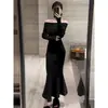 Vestido Preto Sexy com Gola One-Line de Manga Longa para Mulheres no Outono e Inverno Novo Estilo Cintura Emagrecedora Visual que Abraça os Quadris Cauda de Peixe Longa