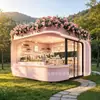Tienda de postres tipo cápsula espacial rosa con esquinas redondeadas, decorada con plantas florales y verdes en la parte superior, una cafetería y tienda de bebidas popular en una zona montañosa escénica