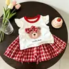 Conjunto de verano dulce de dibujos animados transfronterizo europeo y americano para niños con mangas volantes, falda de cuadros de oso de dibujos animados, conjunto dulce