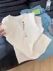 Camiseta Blanca de Punto de Manga Corta con Botones de Colores Coreana para Mujer Verano 2025 Nuevo Diseño Súper Popular que Reduce la Edad Top