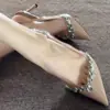 Nueva colección otoño/invierno 2024: Exquisitos zapatos de tacón alto negros para mujer con punta fina y adornos de pedrería, que presentan un delicado tacón de aguja y un elegante diseño de charol color nude.