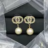 Versión de Alta Gama de los Pendientes de Perlas Chanel Doble C con un Tacto Lujoso, Presentando un Estilo de Nicho y Agujas de Plata 925, Hechos de Material de Latón