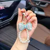 Llavero de lazo de moda con diamantes completos y cadena de perlas, un colgante lindo y brillante para bolsos, cadenas de teléfono y accesorios