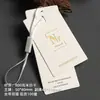Tienda de ropa de alta gama: Etiquetas hechas a medida para ropa de mujer, incluyendo etiquetas, etiquetas colgantes, logotipos y tarjetas color marfil con impresión de lámina dorada.