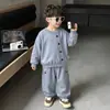 Conjunto casual simple estilo coreano para primavera y otoño para niños, que consta de una camisa de manga larga de color liso con botones y pantalones tipo jogger holgados.