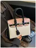 Bolso de mano de alta gama para mujer, nuevo modelo 2026, bolso Kelly de moda transfronterizo, bolso de hombro y cruzado casual para el trabajo, color platino