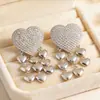 Pendientes de botón con forma de corazón de diamantes de imitación y borla, moda simple transfronteriza europea y americana, pendientes con sentido de diseño de nicho, adornos para orejas de sentido de lujo ligero de alta gama