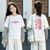 Camiseta de manga larga tipo dos piezas de imitación para niños, colección otoño 2026, para niñas, 100% algodón, cuello redondo, corte holgado, diseño lindo de caricatura, top básico
