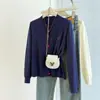 Foto real de suéter cardigã de tricô oversized com fio core de outono e inverno para mulheres, adequado para usar tanto por dentro quanto por fora, com botões bordados em formato de coração