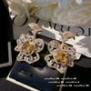 Pendientes de flor con gema de color turmalina canaria bañados en oro de 18 quilates y pétalos de circonita amarilla crepuscular.