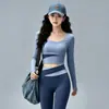 Conjunto de fitness Pilates sin costuras y apto para la piel para mujer, con un top de manga larga de cuello redondo y bloques de color, y unos leggings de cintura alta con diseño cruzado que levantan y moldean las caderas