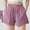Conjunto de atuendo de yoga para mujer con un ambiente brumoso y relajado, que presenta un top elegante y versátil de corte holgado con un escote asimétrico y shorts con cintura elástica anti-exposición