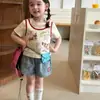 Conjunto de duas peças de desenho animado para meninas: top de manga curta + shorts jeans patchwork, novo estilo simples e versátil para o verão de 2026