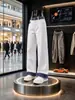 Calça jeans branca para homens, com patchwork de estampa de cobra em cores contrastantes, bainha dobrada, estilo vibe americana, design único e levemente alargada.