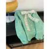 Suéter estiloso com acabamento em renda e gola redonda, apresentando design de amarrar, um botão dourado em formato de coração e modelagem solta, perfeito para o outono e inverno.